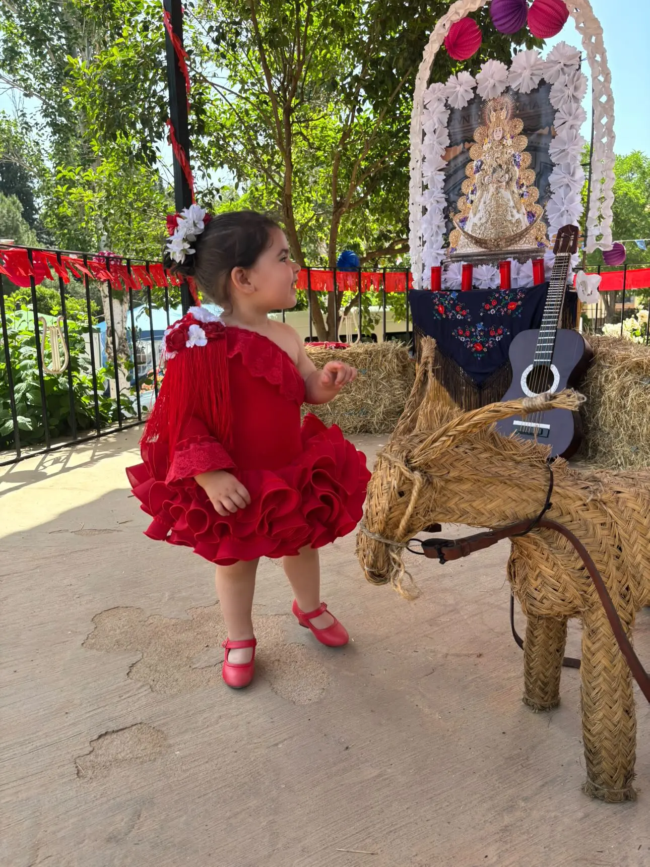 Niña vestida de flamenca junto al photocall de la feria
