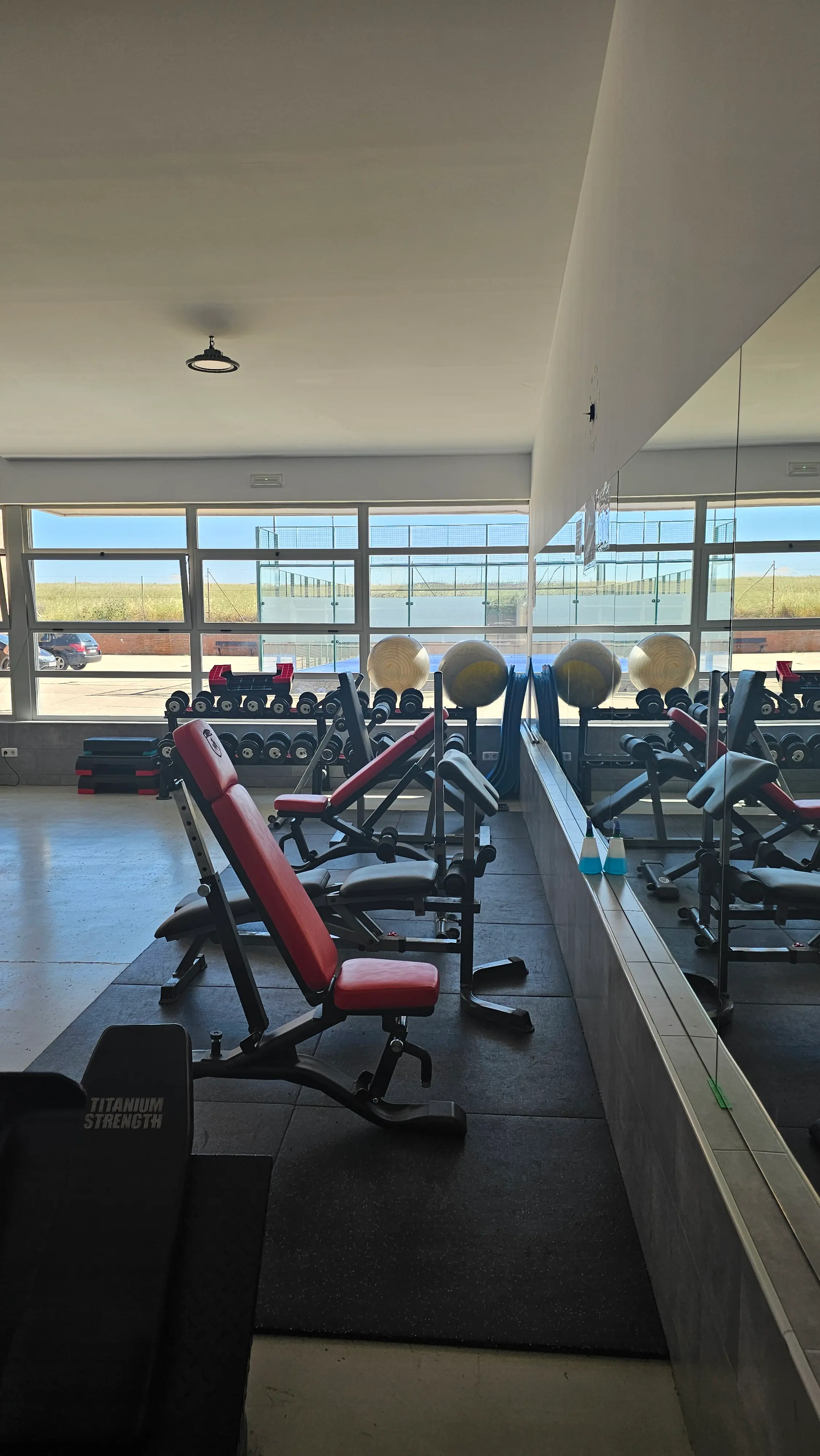 Área de bancos y mancuernas del gimnasio de Los Navalmorales con luz natural