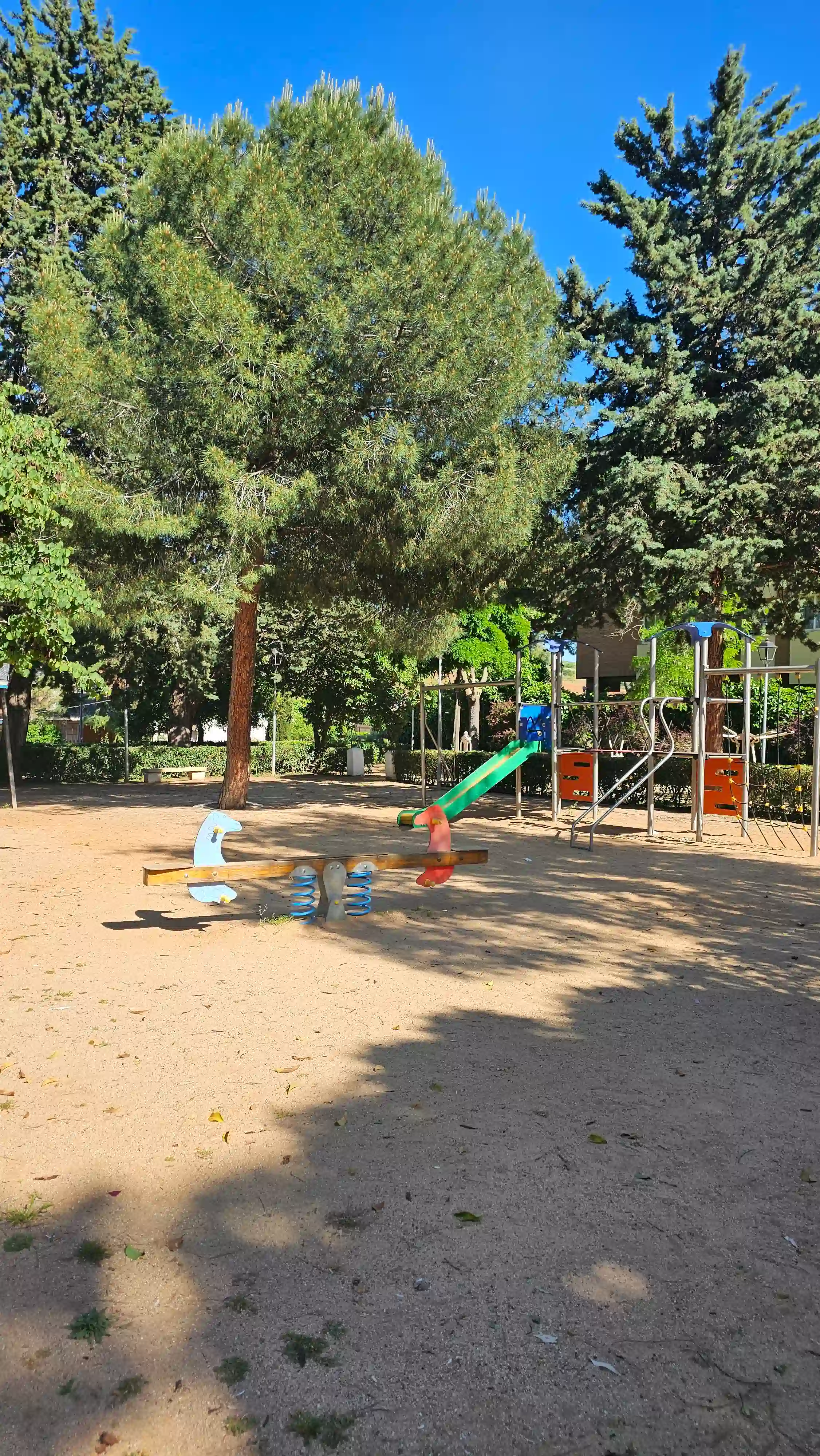 Zona de juegos infantiles con columpios y toboganes en el parque de Los Navalmorales